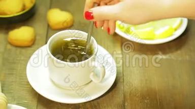 一个女人把刚泡好的绿茶和勺子混合在白色的杯子里